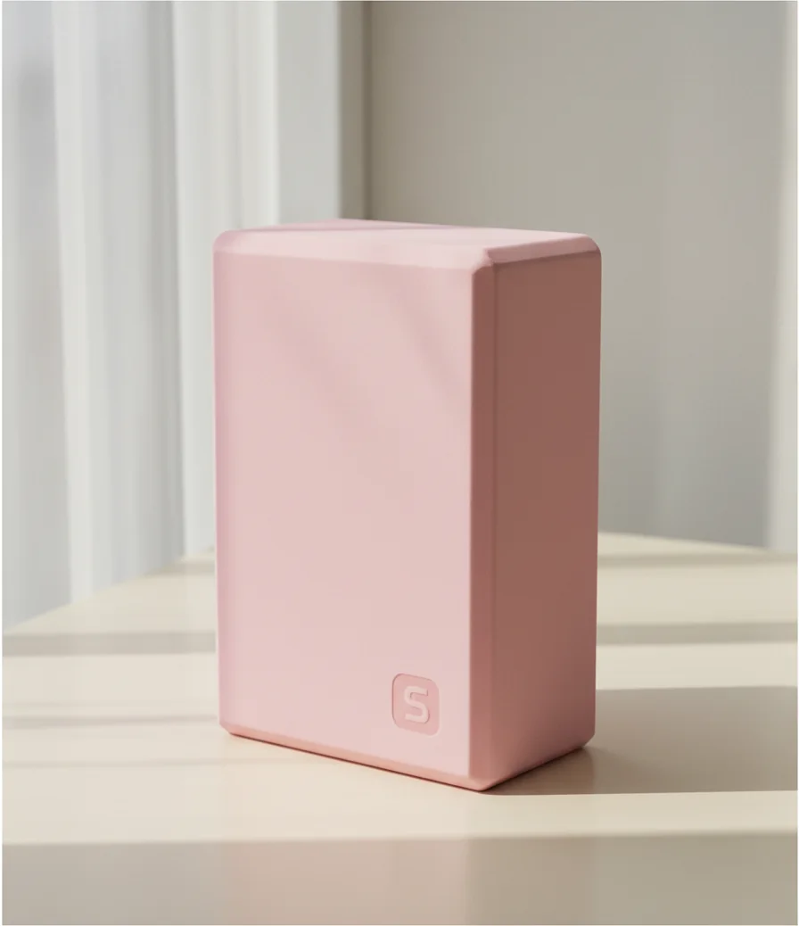 Pale pink foam yoga block standing on its end, with a small embossed S emblem